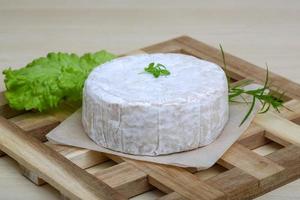 queso camembert sobre tabla de madera y fondo de madera foto