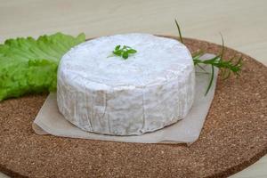 Brie cheese on wooden board and wooden background photo