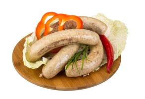 Grilled sausages on wooden board and white background photo