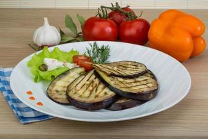 Grilled aubergine on the plate and wooden background photo