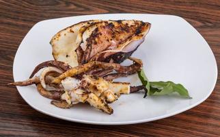 Grilled cuttlefish on the plate and wooden background photo