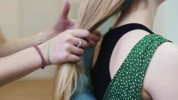 Langes blondes Haar wird von Händen mit roten Nägeln zu einem grünen Gummiband gebunden video