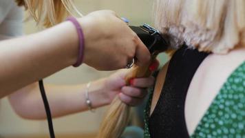 mujer cortándose el pelo largo con una recortadora