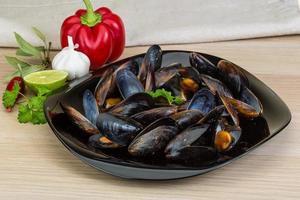 Mussels on the plate and wooden background photo