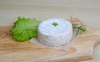 queso camembert sobre tabla de madera y fondo de madera foto