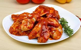 Chicken wings on the plate and wooden background photo