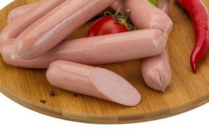 Sausages on wooden board and white background photo