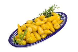 Yellow marinated pepper in a bowl on white background photo