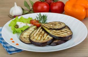 Grilled aubergine on the plate and wooden background photo