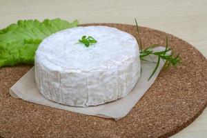 queso brie sobre tablero de madera y fondo de madera foto