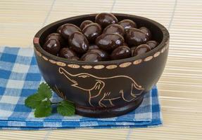 Almond in chocolate in a bowl on wooden background photo