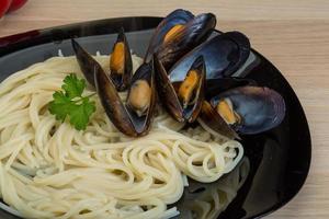 pasta con mejillones en el plato y fondo de madera foto