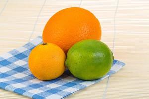 Orange, lime, tangerine on wooden background photo