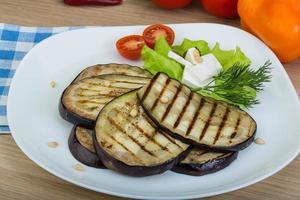 berenjena a la parrilla en el plato y fondo de madera foto