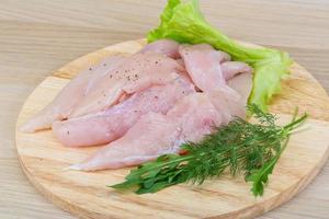 Raw chicken breast on wooden board and wooden background photo