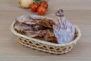 Dried squid in a basket on wooden background photo