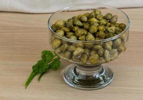 Capers in a bowl on wooden background photo