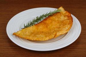 Meat Cheburek on the plate and wooden background photo