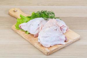 Raw chicken thighs on wooden board and wooden background photo