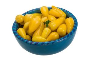 Yellow marinated pepper in a bowl on white background photo