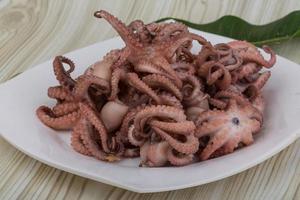 Boiled octopus on the plate and wooden background photo