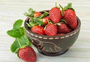 Fresh strawberry in a bowl on wooden background photo