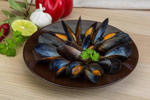 Mussels on the plate and wooden background photo