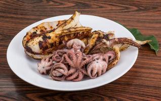 Boiled octopus on the plate and wooden background photo