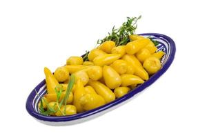 Yellow marinated pepper in a bowl on white background photo