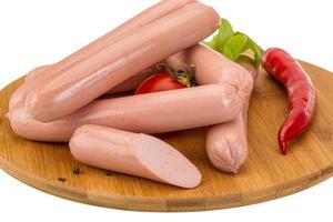 Sausages on wooden board and white background photo