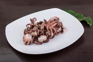 Boiled octopus on the plate and wooden background photo