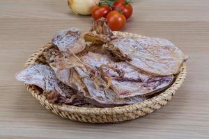 Dried squid in a basket on wooden background photo