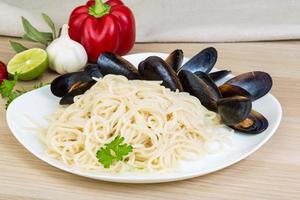 pasta con mejillones en el plato y fondo de madera foto