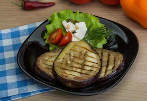 Grilled aubergine on the plate and wooden background photo