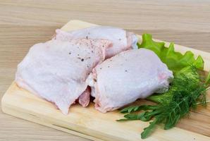 Raw chicken thighs on wooden board and wooden background photo