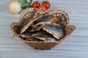 pescado seco en una cesta sobre fondo de madera foto
