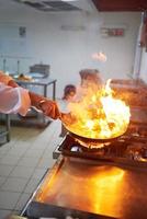 chef en la cocina del hotel prepara comida con fuego foto