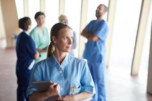 female doctor with tablet computer  standing in front of team photo