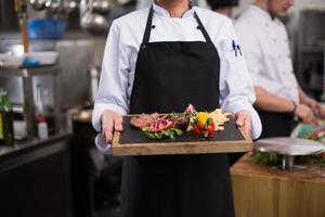 female Chef holding beef steak plate photo