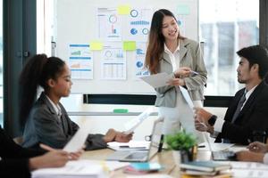 Female Operations Manager Holds Meeting Presentation for a Team of Economists. Asian Woman Uses Digital Whiteboard with Growth Analysis, Charts, Statistics and Data. People Work in Business Office. photo