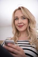 woman sitting on sofa with mobile phone photo