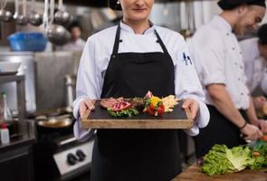 female Chef holding beef steak plate photo