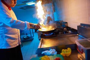 chef in hotel kitchen prepare food with fire photo