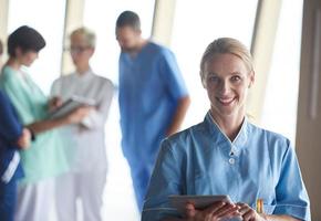 female doctor with tablet computer  standing in front of team photo