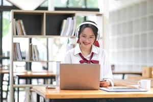 estudiante asiática en línea, clase de aprendizaje, estudio en línea, videollamada, profesor de zoom, niña asiática feliz, aprende inglés en línea con una computadora portátil. foto