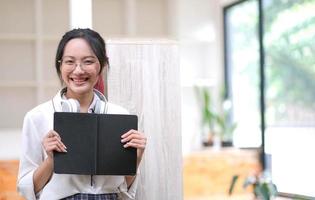 Young asian business woman is standing at a desk and taking notes in a notebook. The concept of education and technology. photo