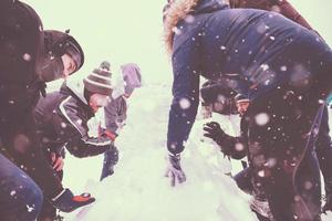 group of young people making a snowman photo