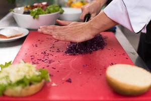 chef manos cortando ensalada para hamburguesa foto