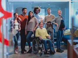 Disabled businesswoman in a wheelchair at the office with coworkers team photo