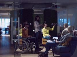 Disabled businessman in a wheelchair at work in modern open space coworking office with team using virtual reality googles drone assistance simulation photo